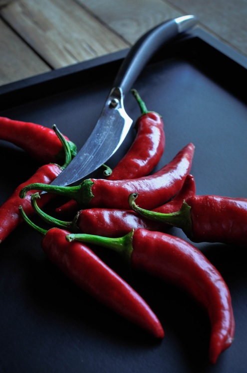 Chillies and knife on black tray